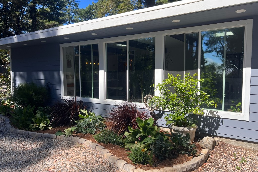 Residence exterior with window wall and planted garden bed
